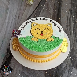 Bánh kem vẽ chú mèo vàng nằm trên thảm cỏ  